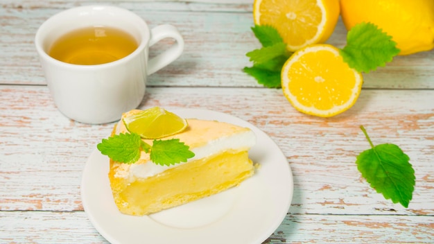 Torta al limone appetitosa tazza di tè e limoni su fondo di legno