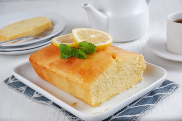 Torta al limone con teiera bianca e una tazza di caffè con sfondo sfocatosfondo bianco