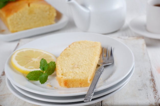 Torta al limone con teiera bianca e una tazza di caffè con sfondo sfocatosfondo bianco