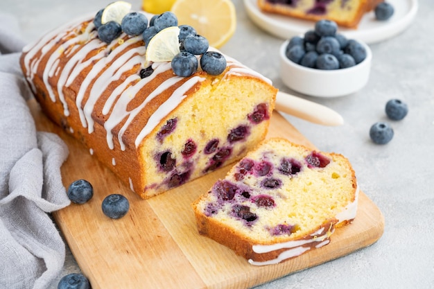 Torta al limone e mirtilli con glassa al limone e frutti di bosco freschi sulla tavola con una tazza di tè