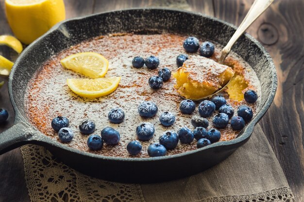 Torta al limone fatta in casa fresca in padella di ferro su legno rustico