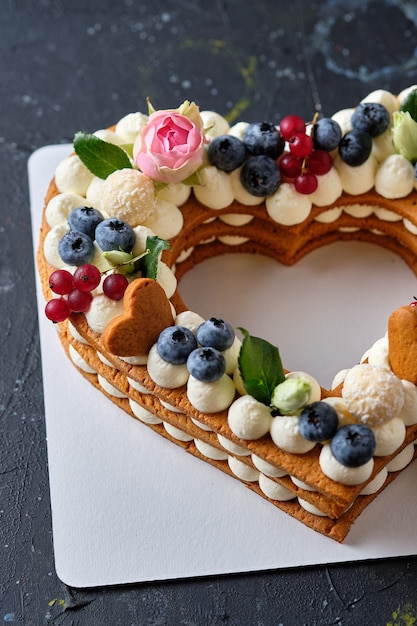 Torta al miele con mirtilli freschi, erbe aromatiche e crema di formaggio cremoso. Dessert per una persona cara. Torta di cuore.