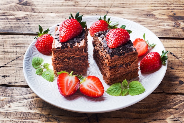 Torta al tartufo al cioccolato con fragole e menta. Tavolo di legno.