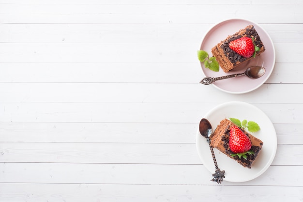 Torta al tartufo con cioccolato e fragole e menta su un tavolo di legno bianco.