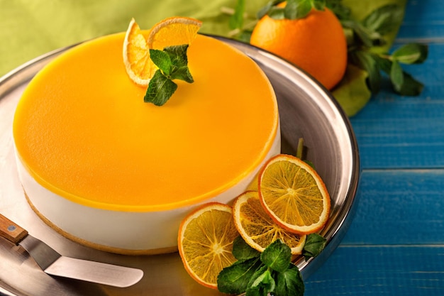 Torta all'arancia in piatto bianco sul tavolo di legno blu