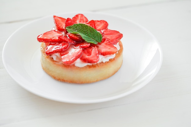 Torta alla fragola sul fuoco selettivo del fondo della tavola di legno bianca