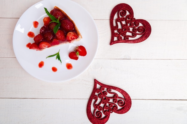 Torta alle fragole sul piatto bianco e tavolo in legno bianco,