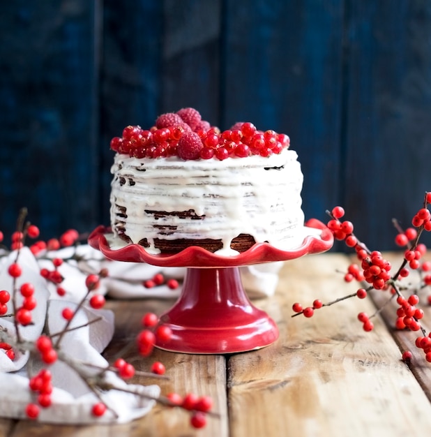 Torta bianca con bacche rosse su fondo in legno