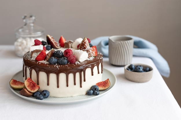 Torta bianca con diversi frutti di bosco e cioccolato su tovaglia di lino Compleanno Festa della mamma concept