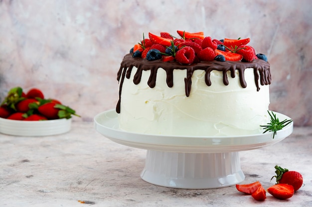 Torta bianca con glassa al cioccolato e frutti di bosco freschi.