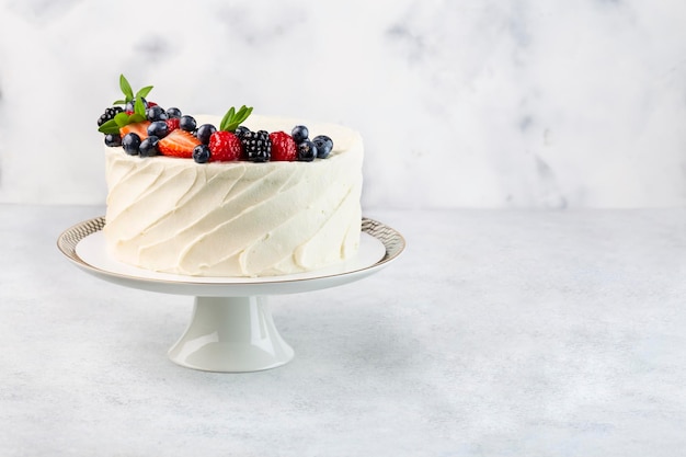 Torta bianca con una corona di fragole e mirtilli e lamponi su fondo bianco