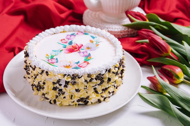 Torta bianca decorata con crema vicino a tulipani rossi