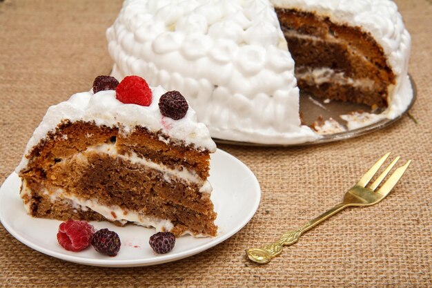 Torta biscotto fatta in casa a fette decorata con forcella in metallo panna montata sul tavolo con tela di sacco