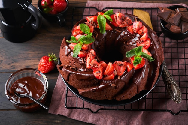 Torta Bundt al cioccolato fondente con glassa di Ganache e fragola su pietra scura o sfondo del tavolo in cemento Torta festiva Messa a fuoco selettiva