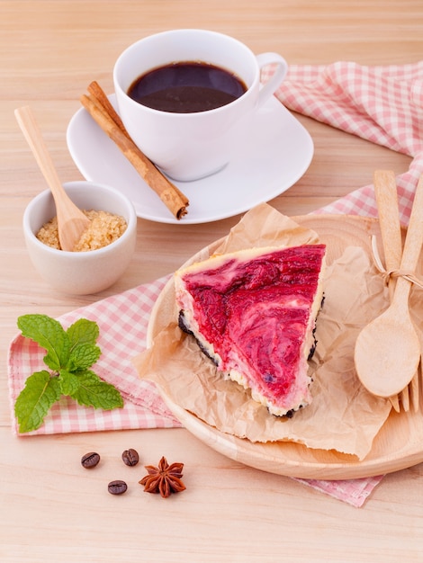 Torta casalinga del lampone con la tazza di caffè su fondo di legno.