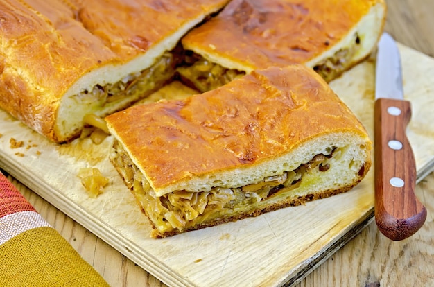 Torta con cavoli e finferli, coltello, tovagliolo su una tavola di legno