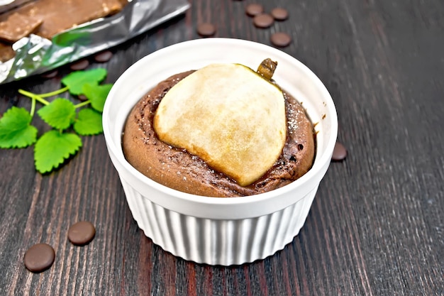 Torta con cioccolato e pera in una ciotola bianca menta sullo sfondo di assi di legno