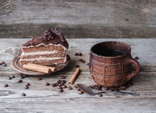 Torta con crema al cioccolato e una tazza da caffè in ceramica su assi di legno