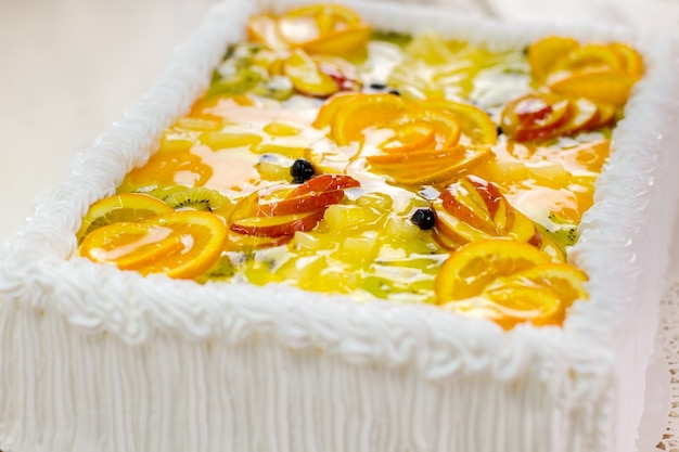 Torta con fette di frutta. Crema bianca e gelatina. È ora di mangiare e festeggiare. Dolce opera d'arte.