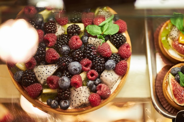 Torta con frutti di bosco freschi sul bancone di vetro nella pasticceria torte con frutti di bosco freschi