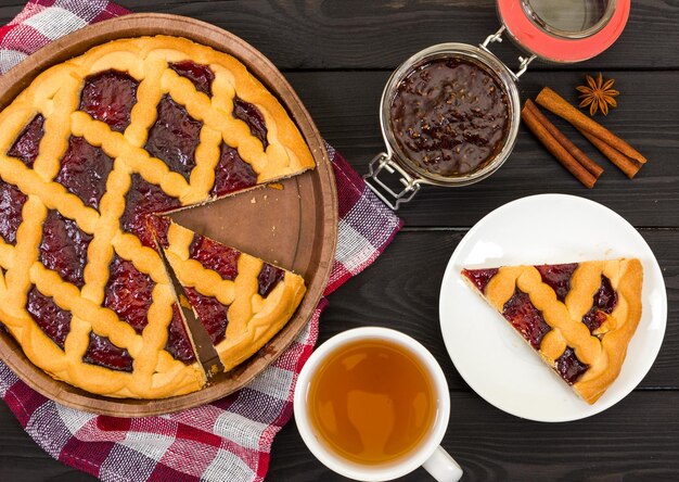 Torta con marmellata e tè su fondo di legno nero