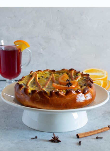 Torta con ripieno all'arancia su un supporto. vin brulé su fondo chiaro, verticale