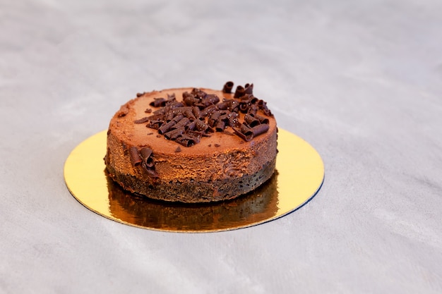 Torta congelata cheesecake al cioccolato su un supporto dorato Sfondo grigio messa a fuoco selettiva spazio copia