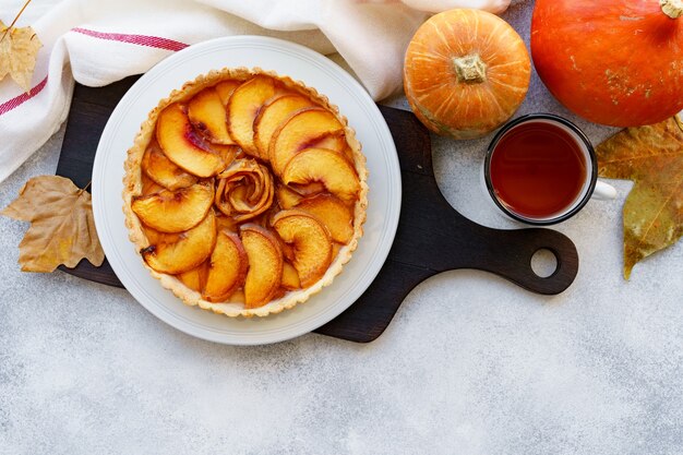 Torta crostata di mele sul tavolo con zucca e foglie secche