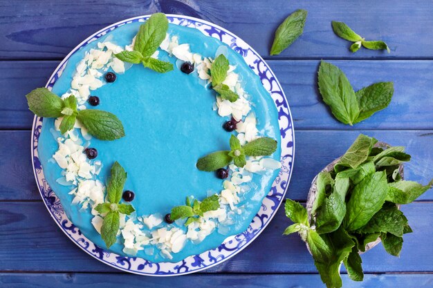 Torta decorata con crema blu, menta e mirtilli.