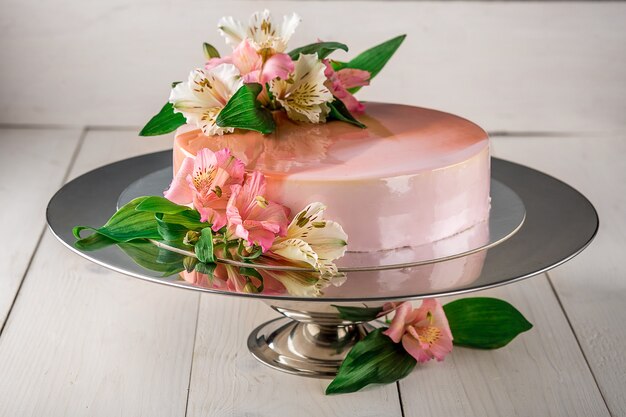 Torta decorata con fiori. Torta nuziale su un supporto su uno sfondo di legno bianco