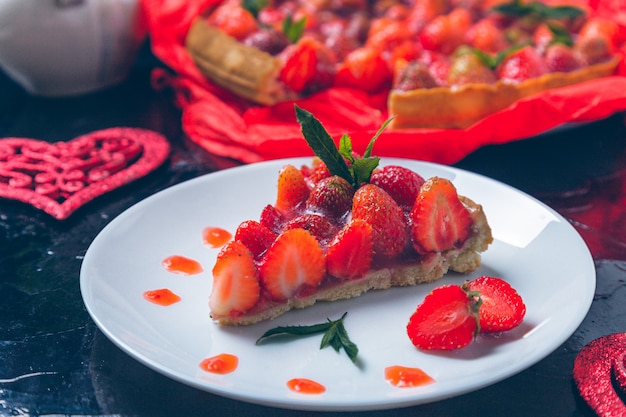 Torta della fragola sulla tavola di legno del nero bianco del piatto.