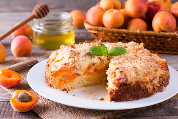 Torta di albicocche fatta in casa con frutta fresca sul tavolo in legno rustico