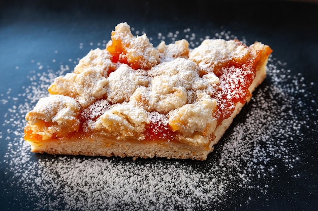 Torta di albicocche fatta in casa Una fetta di torta dolce calda rustica in zucchero a velo su un piatto nero