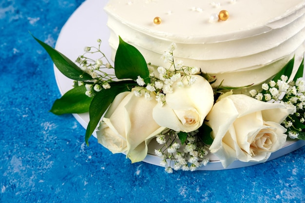 Torta di anniversario con rose bianche su sfondo blu. Avvicinamento.