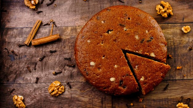 Torta di carote decorata con bastoncini di cannella e noci