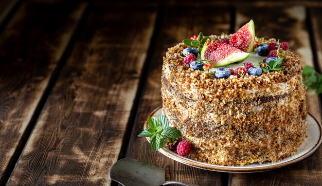 Torta di carote decorata con frutti di bosco e fichi su un legno. Dolci tradizionali a base di asini.