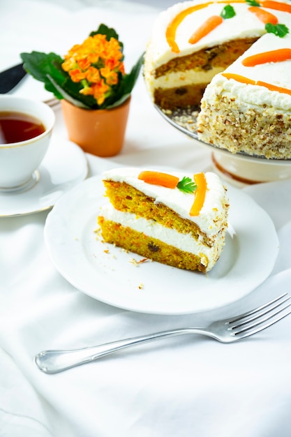 Torta di carote su un piatto bianco con una forchetta, tovaglia bianca