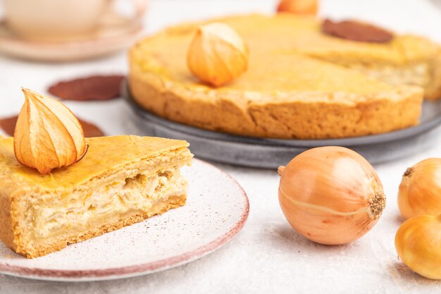 Torta di cipolle autunnale decorata con foglie e tazza di caffè su cemento grigio