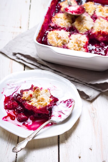 Torta di cobbler di ciliegie fatta in casa con crosta traballante, gelato, cucchiaio vintage