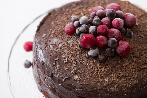 Torta di compleanno al cioccolato fresca fatta in casa con frutti di bosco surgelati biologici e patatine sulla parte superiore