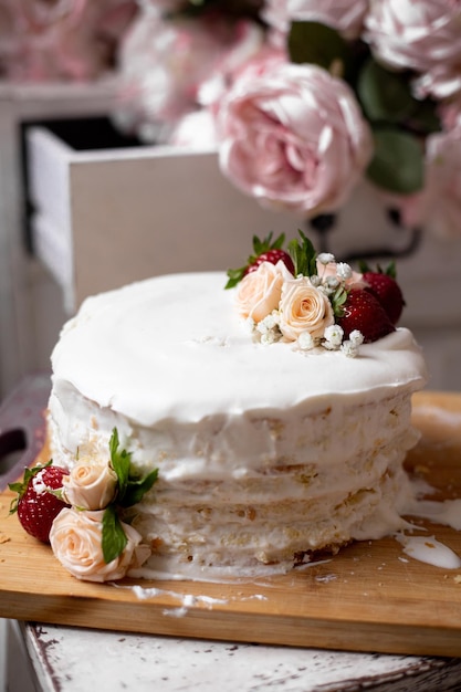 Torta di compleanno con decorazioni di fiori naturali e fragole su tavola di legno