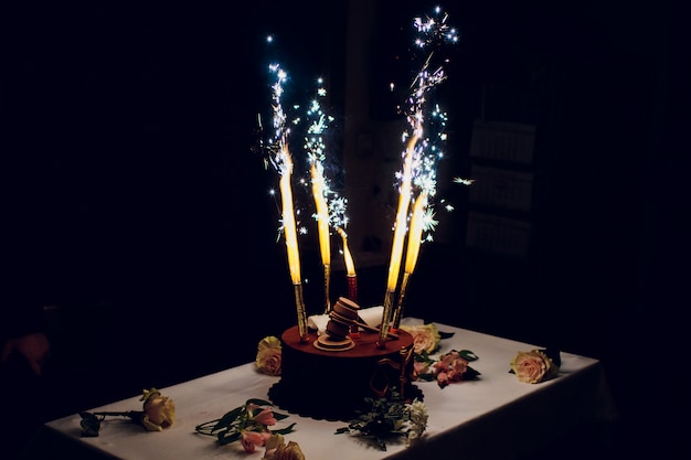 Torta di compleanno con fuochi d'artificio sul tavolo