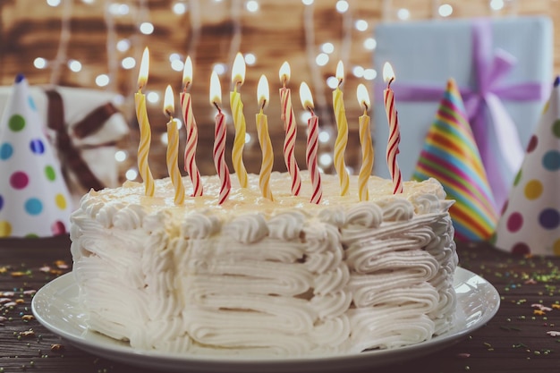 Torta di compleanno con le candele su sfondo di luci