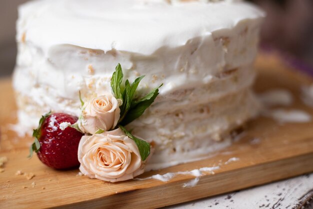 Torta di compleanno con un decoro di fiori naturali e fragole su una tavola di legno torta di crema di formaggio biscotto alla vaniglia per una vacanza