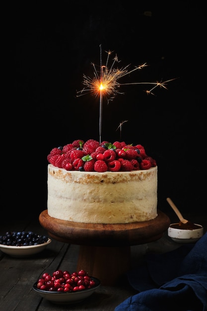 Torta di compleanno festiva con bellissime stelle filanti. Torta con lamponi, frutti di bosco e ikokos.