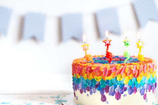 Torta di compleanno multicolore decorata con crema e candele. Concetto di festa di compleanno.