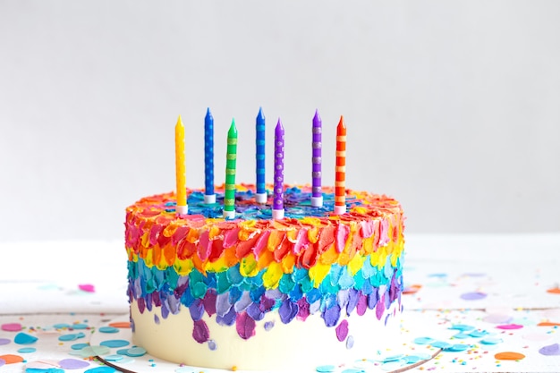 Torta di compleanno multicolore decorata con crema e candele. Concetto di festa di compleanno.