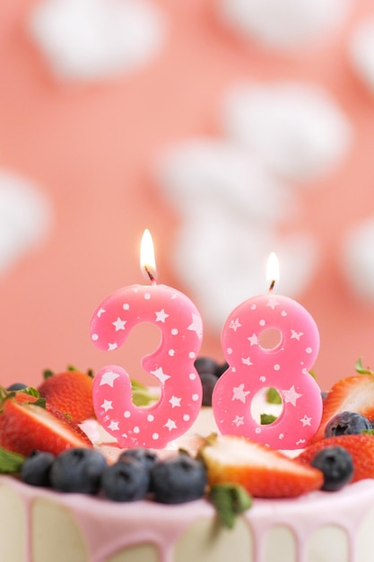 Torta di compleanno numero 38 Bella candela rosa in torta su sfondo rosa con nuvole bianche Vista in primo piano e verticale