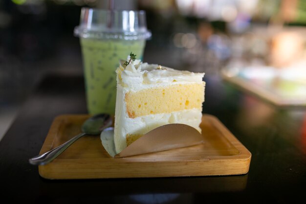 Torta di formaggio a crema con tè verde su piatto di legno in un caffè