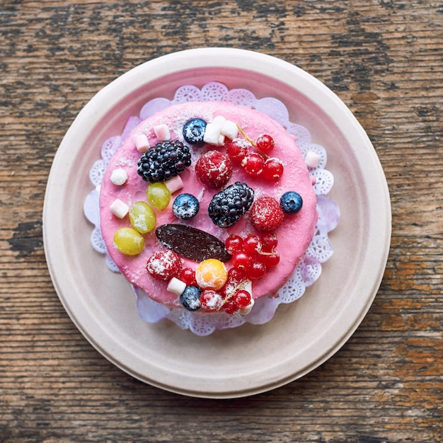 Torta di formaggio dolce con frutti di bosco freschi e crema allo yogurt. Deliziosa torta di lamponi con fragole fresche, lamponi, mirtilli, ribes e frutti di mora su superficie di legno rustico